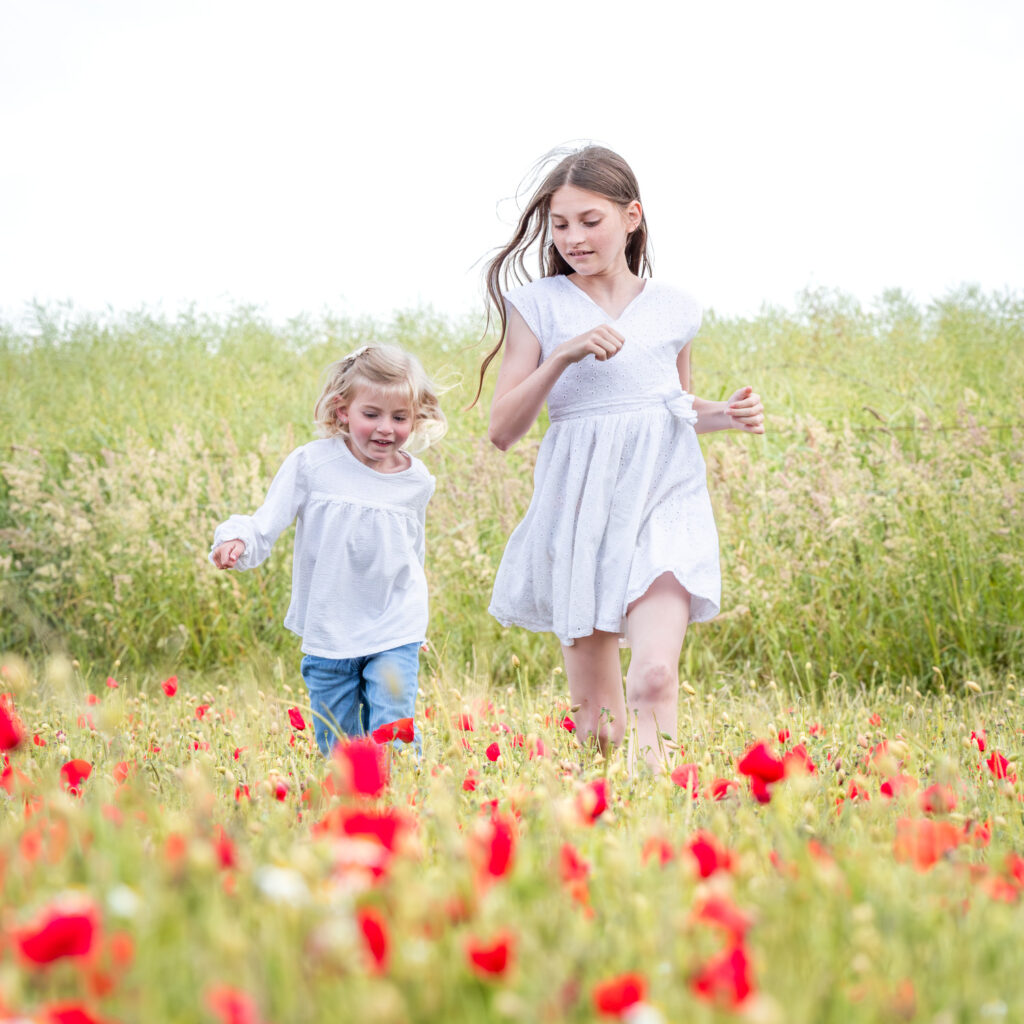Enfants riant et courant parmi les coquelicots sous la lumière dorée du soir